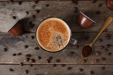 Tahta masada bir fincan lezzetli kahve, kapsül ve fasulye.