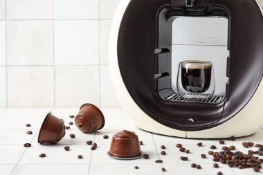 Modern kapsül kahve makinesi beyaz masada bir fincan espresso, kapsül ve fasulye.