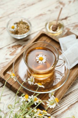 Hafif ahşap arka planda bir fincan sıcak papatya çayı.