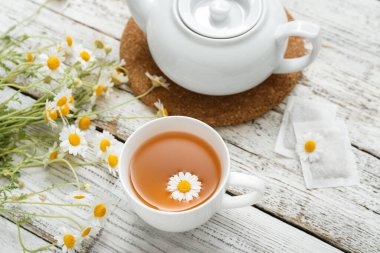 Hafif ahşap arka planda bir fincan sıcak papatya çayı.