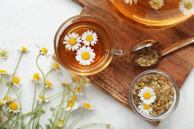 Cup of hot chamomile tea on light background clipart