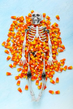 Lezzetli Cadılar Bayramı şekerlemeleri ve mavi arka planda iskelet