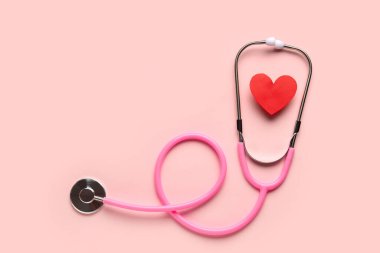 Stetoskop ve pembe arka planda kırmızı kalp. Kardiyoloji kavramı