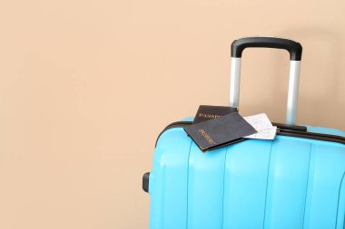 Pasaportlu bavul ve soluk turuncu arka planda biletler. Seyahat kavramı