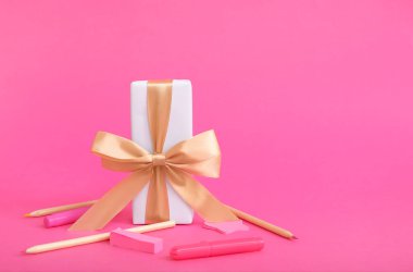 Pembe arka planda farklı kırtasiye malzemesi olan hediye kutusu