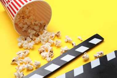 Sarı arka planda lezzetli patlamış mısır ve el çırpma tahtası olan kova.