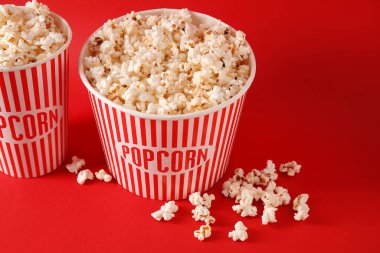 Kırmızı arka planda lezzetli patlamış mısır kovaları