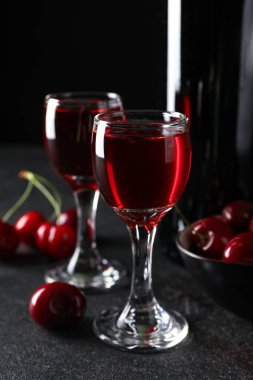 Siyah zemin üzerinde vişne likörü olan bardaklar.