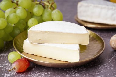 Gri arka planda lezzetli Camembert peyniri parçaları ile tabak.