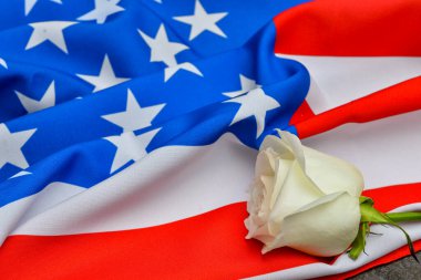 Arka planda Amerikan bayrağı olan gül çiçeği. Terörist Saldırıları Mağdurları İçin Ulusal Namaz ve Anma Günü