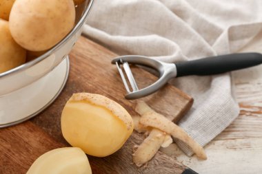 Beyaz ahşap arka planda çiğ patatesli tahta, yakın plan.