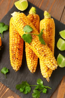 Lezzetli ızgara mısır koçanı ve ahşap arka planda limon.