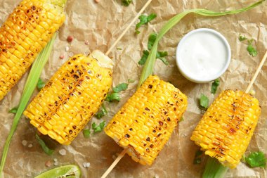 Lezzetli ızgara mısır koçanı şiş ve soslu kağıt, yakın plan.