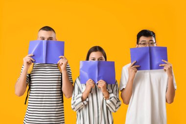 Sarı arkaplan üzerine not defterleri olan öğrenciler