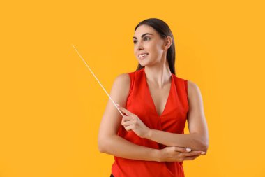 Sarı arka planı olan genç bir bayan öğretmen.