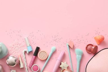 Pembe arka planda makyaj ürünleri ve Noel süslemeleri