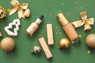 Makyaj ürünleri ve koyu yeşil arka planda altın Noel dekoru.