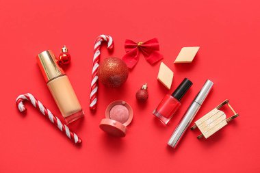 Kırmızı arka planda dekoratif kozmetik ve Noel dekoru olan kompozisyon