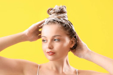 Young woman washing hair on yellow background, closeup clipart