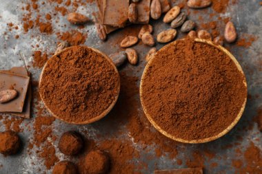 Siyah arka planda kakao tozu, şeker, fasulye ve çikolata dolu kaseler