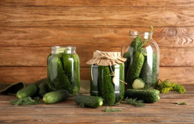 Taze ve konserve salatalıklı kavanozlar ahşap arka planda