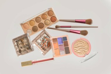 Beyaz arka planda farklı dekoratif kozmetik ürünleri ve fırçalar