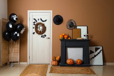 İçinde şömine, balon, kapı ve Cadılar Bayramı süslemeleri olan festival koridoru.