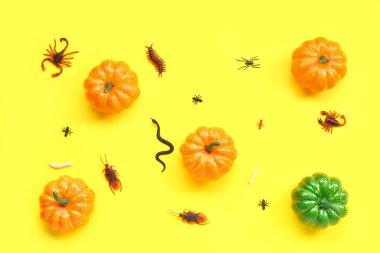 Sarı arka planda şeker böcekleri ve balkabaklarıyla Cadılar Bayramı kompozisyonu