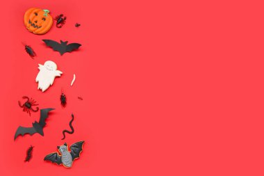 Kırmızı zemin üzerinde yarasalar, şeker böcekleri ve balkabağı olan Cadılar Bayramı kompozisyonu