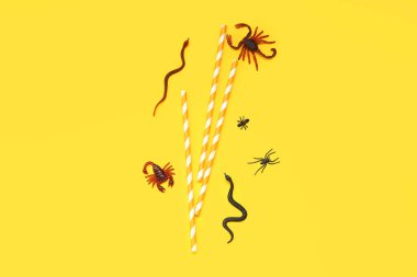 Sarı arka planda şeker böcekleri ve pipetlerle Cadılar Bayramı kompozisyonu