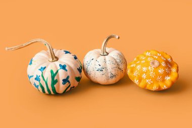 Renkli Cadılar Bayramı balkabakları turuncu arka planda çiçekler