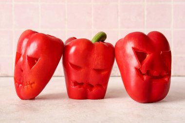 Cadılar Bayramı için pembe fayans duvarının yanındaki masaya dolgu biber oydum.