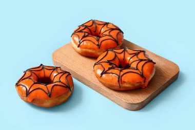 Mavi arka planda Cadılar Bayramı için lezzetli donutları olan ahşap tahta tahta.