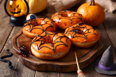 Cadılar Bayramı için lezzetli çörekler, şeker, cadı şapkası ve tahta arka planda süpürge.