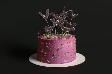 Cadılar Bayramı için siyah arkaplanda süslenmiş lezzetli bir pasta.