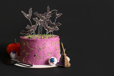 Cadılar Bayramı için siyah arkaplanda süslenmiş lezzetli bir pasta.