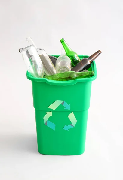 Container for garbage with glass bottles on light background. Recycling concept