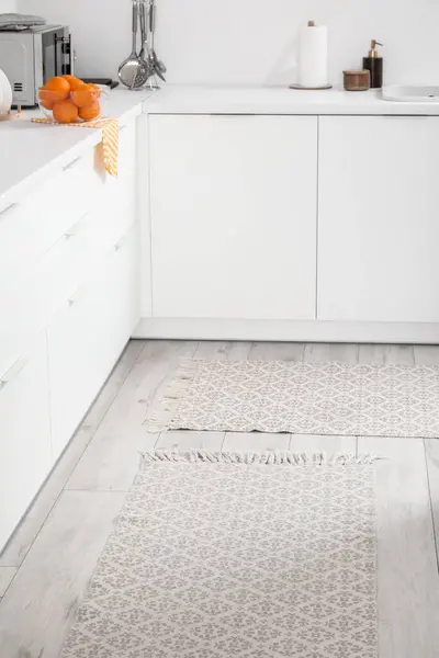 Stylish rug on floor in light kitchen