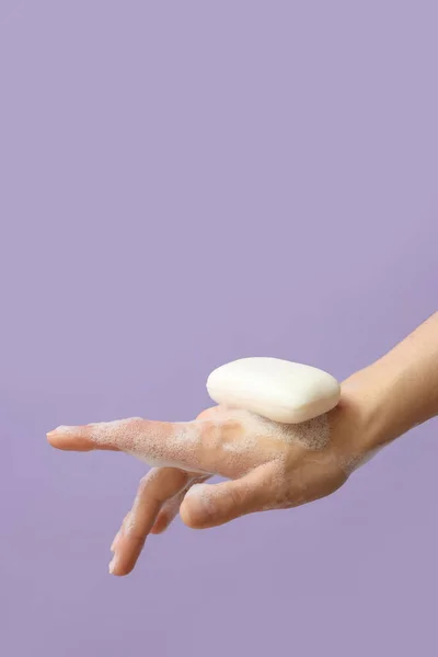Hand with soap on lilac background