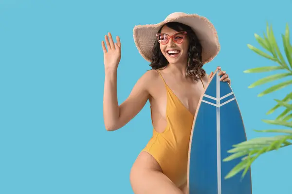 Junge Frau Badeanzug Mit Surfbrett Und Palmblättern Auf Blauem Hintergrund — Stockfoto