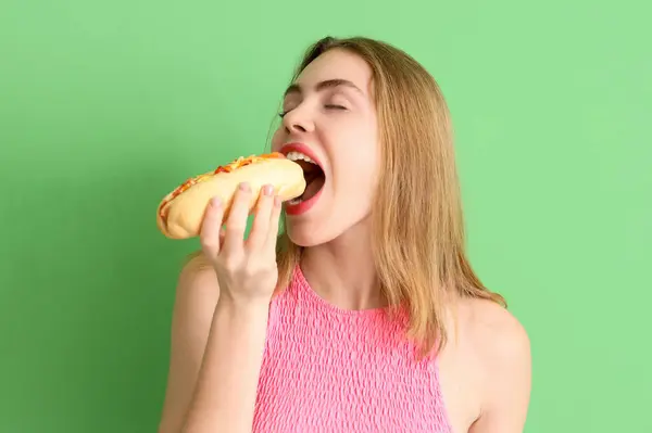Ładna Młoda Kobieta Jedzenie Smaczny Hot Dog Zielonym Tle — Zdjęcie stockowe