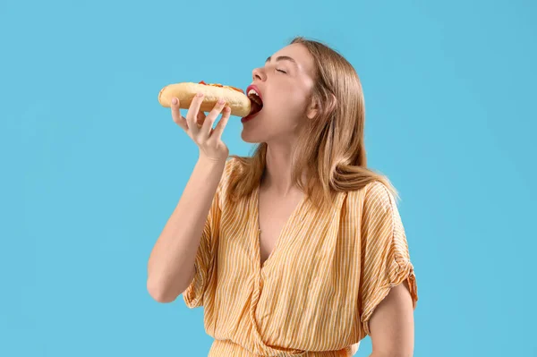 Hübsche Junge Frau Isst Leckeren Hot Dog Auf Blauem Hintergrund — Stockfoto