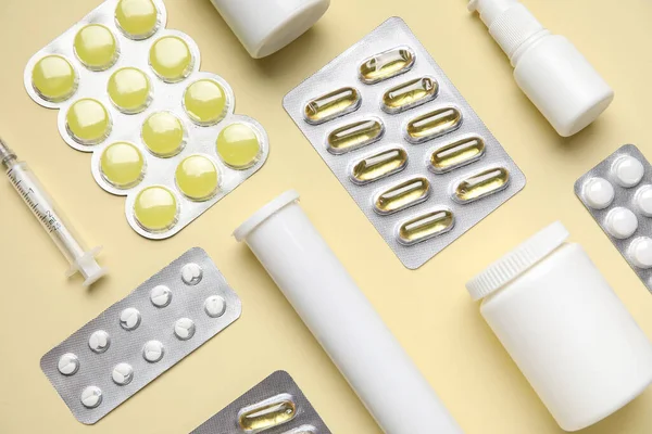 Different pills, syringe and bottles of medicines on yellow background