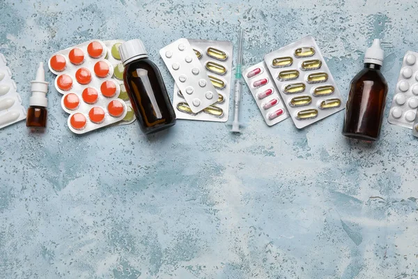 Different pills, syringe and bottles of medicines on blue background