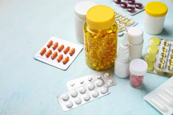 Different pills and bottles of medicines on light blue background