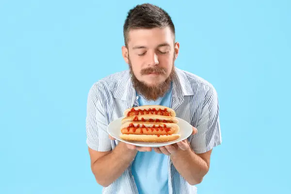 Portrét Pohledného Mladého Muže Vonící Chutné Hot Dogy Talíři Proti — Stock fotografie
