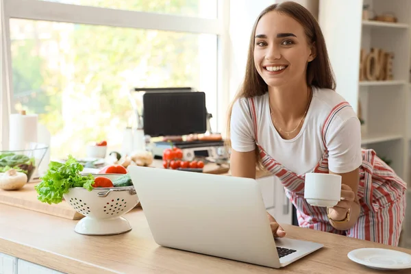 Beautiful Young Woman Using Laptop While Cooking Delicious Sausages Modern — Stock Photo, Image