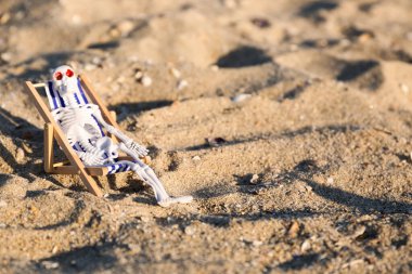 Cadılar Bayramı için iskelet ve kumsalda iskele sandalyesi.