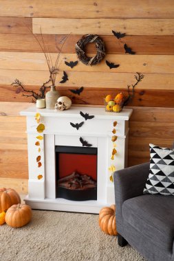 Cadılar Bayramı için dekore edilmiş oturma odasının içinde şömine ve koltuk var.