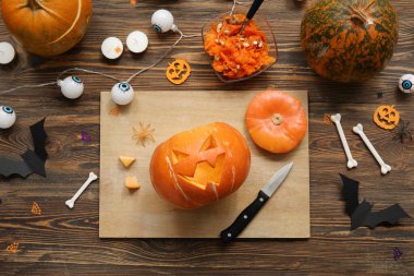 Ahşap masada Cadılar Bayramı süsleriyle oyulmuş balkabağı.